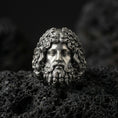 Load image into Gallery viewer, Detailed Zeus head ring crafted in oxidized sterling silver, expressive Greek god facial features, macro product shot on textured volcanic rock background
