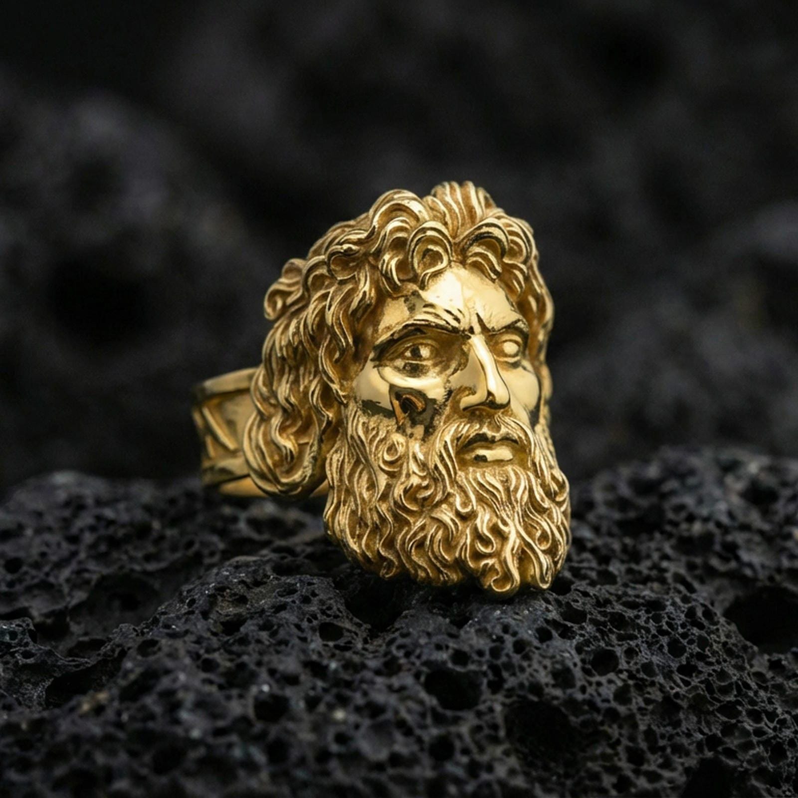 Gold plated Zeus mythology ring featuring classical god portrait and deep relief carving, premium studio macro on black volcanic rock surface