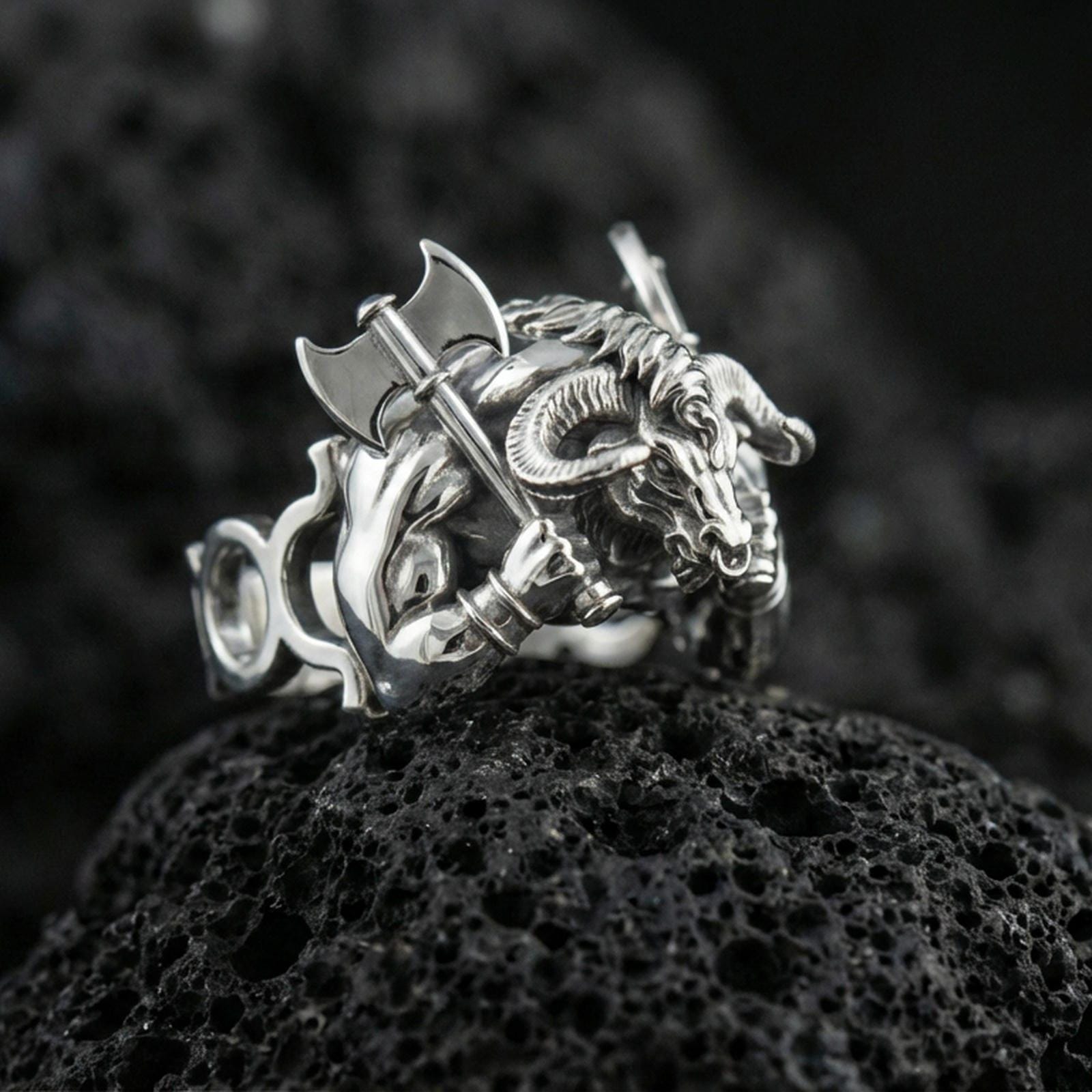 Polished silver Minotaur ring featuring powerful mythological creature with horns and battle axe, centered close-up on dark porous volcanic stone