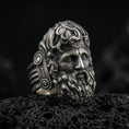 Load image into Gallery viewer, Detailed Zeus ring crafted in oxidized sterling silver, classical Greek god face with flowing beard and ornate curls, macro product shot on textured volcanic rock background
