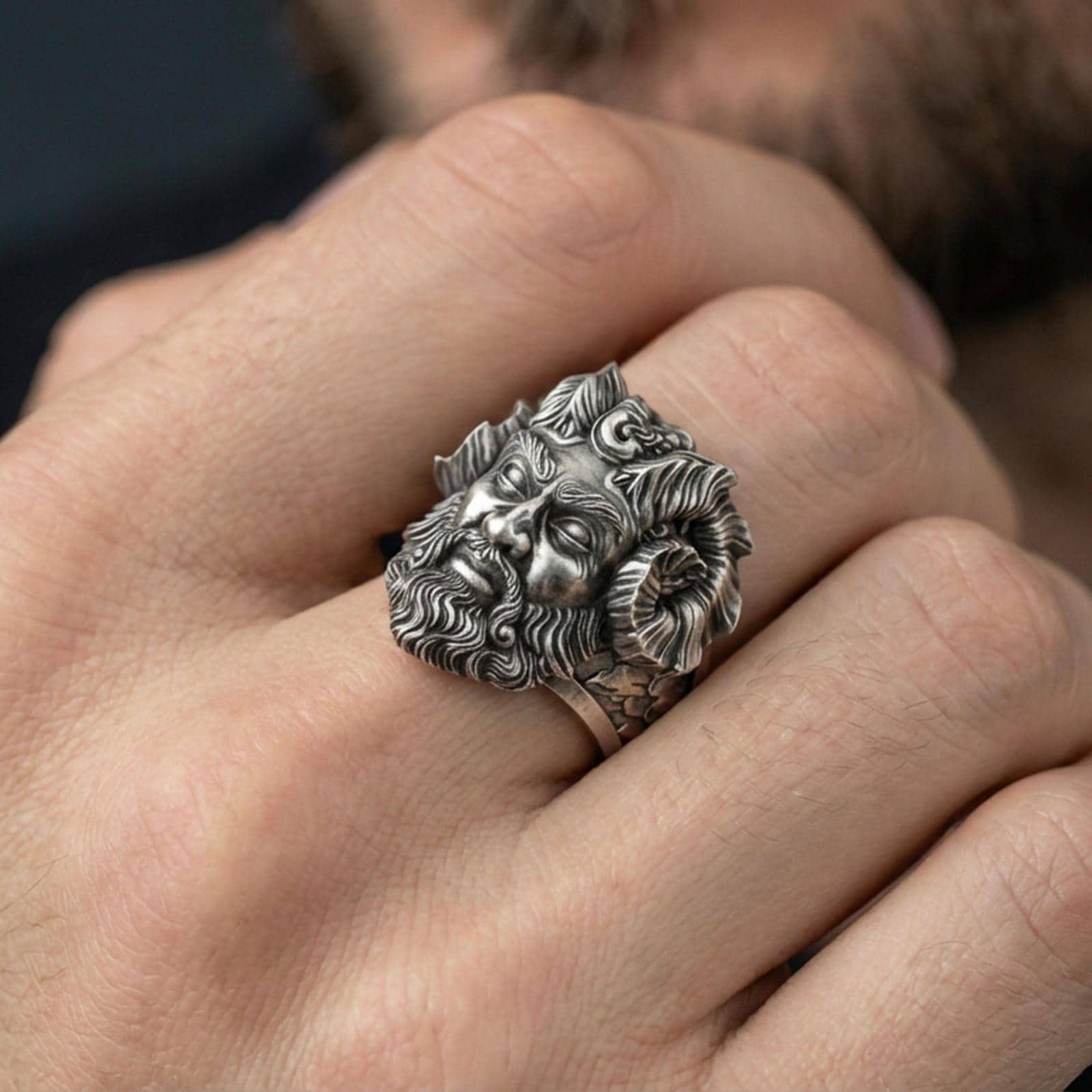 Oxidized sterling silver Czernobog ring worn on finger, bold Slavic mythology design with horned god face and detailed beard, masculine lifestyle hand shot
