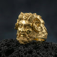 Load image into Gallery viewer, Gold plated Czernobog signet ring with high-relief horned deity head and deep mythological detailing, premium studio macro on black volcanic rock surface
