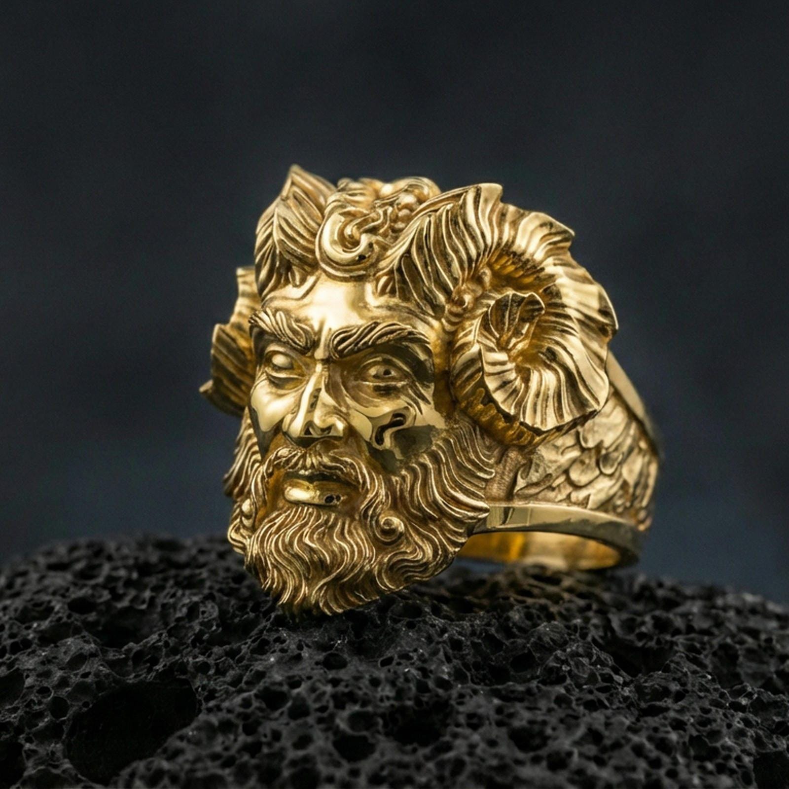 Gold plated Czernobog signet ring with high-relief horned deity head and deep mythological detailing, premium studio macro on black volcanic rock surface