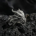 Load image into Gallery viewer, Detailed dragon wyrm ring crafted in oxidized sterling silver, textured scale pattern with horned dragon head, macro product shot on textured volcanic rock background
