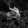 Load image into Gallery viewer, Polished silver dragon ring featuring sculpted horns and intricate reptile scale texture, centered close-up jewelry photo on dark porous volcanic stone
