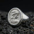 Load image into Gallery viewer, Polished silver Medusa ring featuring sculpted profile with serpent hair and classic Greek key pattern, centered close-up on dark porous volcanic stone
