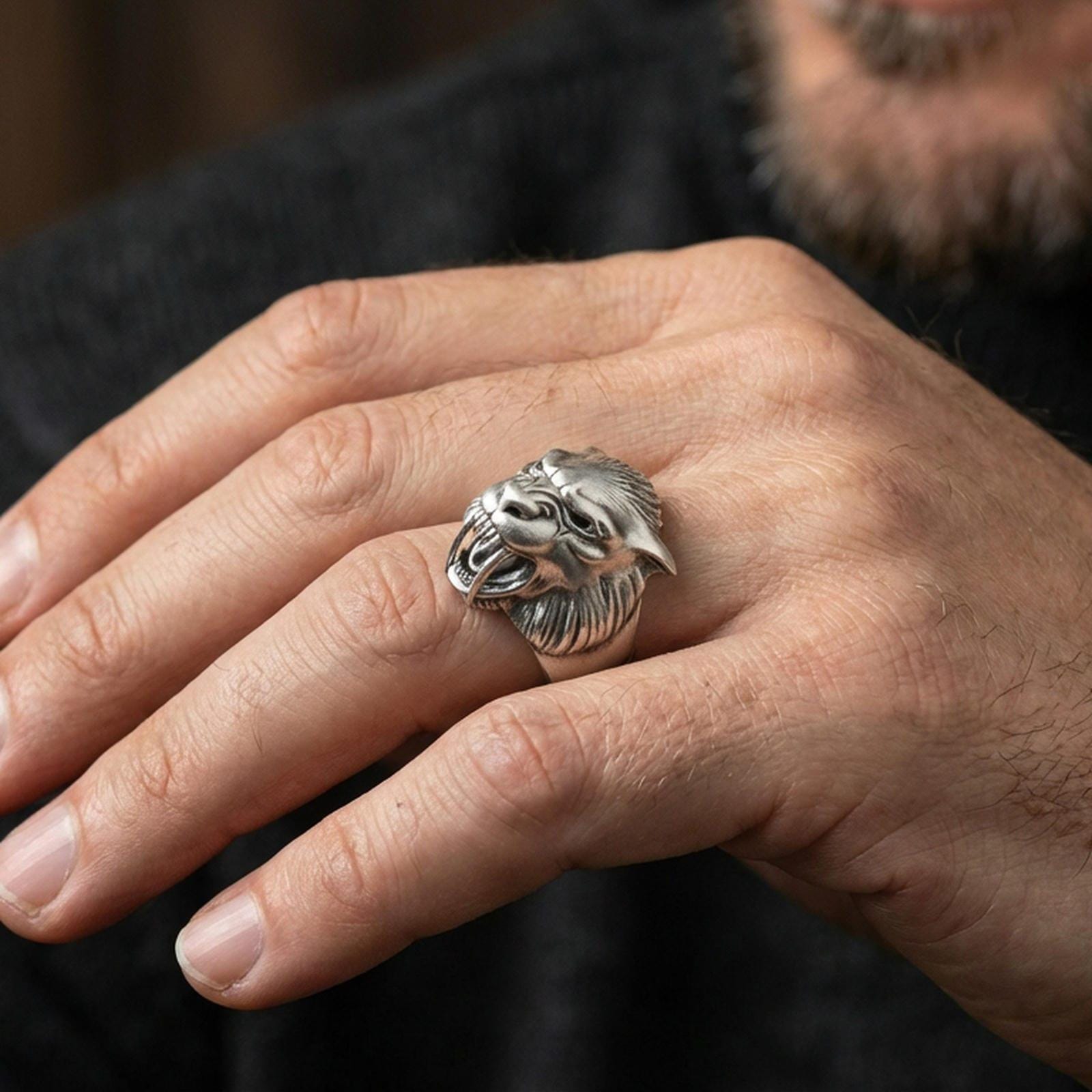 Oxidized sterling silver werewolf head ring worn on finger, bold gothic wolf face with fangs, masculine lifestyle hand shot