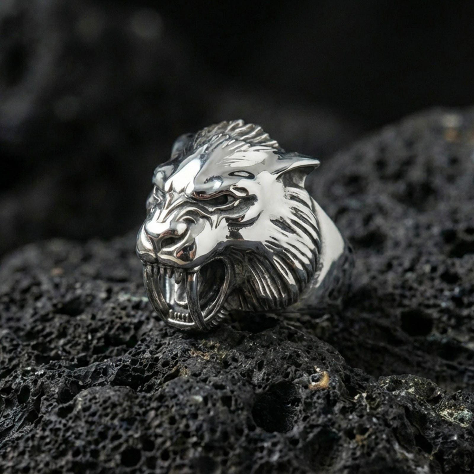 Polished silver werewolf signet ring featuring fierce wolf head sculpture and detailed fur texture, centered close-up on dark porous volcanic stone
