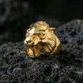Load image into Gallery viewer, Gold plated werewolf head ring with high-relief wolf face and dramatic fangs detail, premium studio macro on black volcanic rock surface
