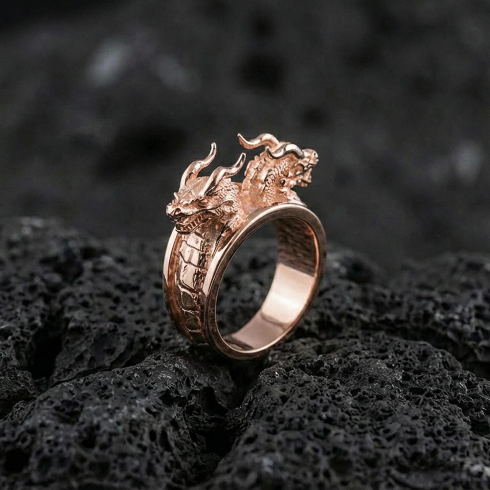 Rose gold plated twin dragons ring showcasing double dragon head motif and detailed scale texture, sharp close-up product photography on volcanic rock
