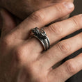 Load image into Gallery viewer, Oxidized sterling silver twin dragons ring worn on finger, open wrap band with two dragon heads and scale texture, masculine lifestyle hand shot
