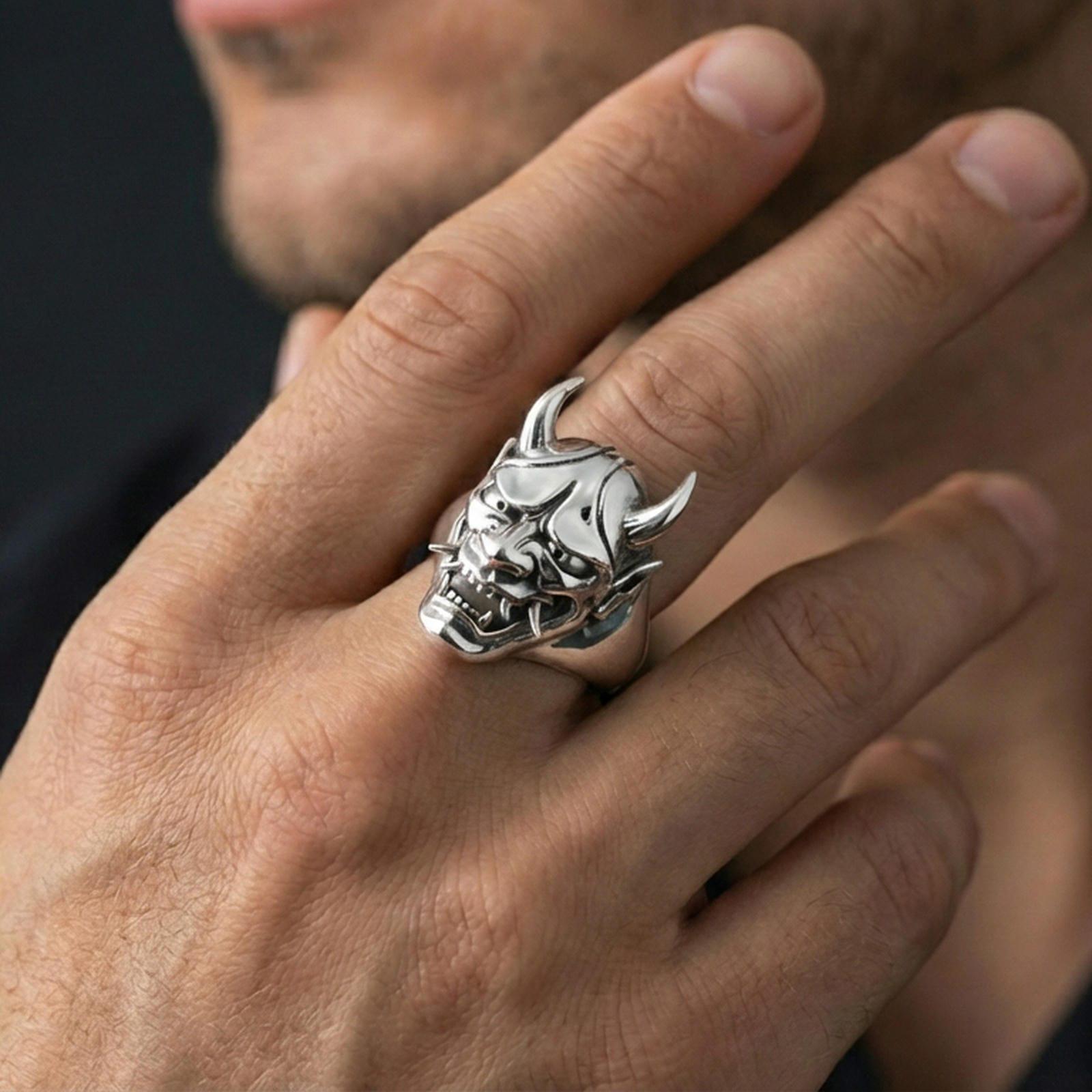 Polished sterling silver Oni mask ring on a human finger, horned demon face signet, crisp sculpted details, heavy statement ring