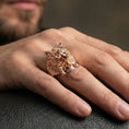 Load image into Gallery viewer, Rose gold plated wolf headdress skull ring on a human finger, wolf head skull signet ring, bold mythic warrior style
