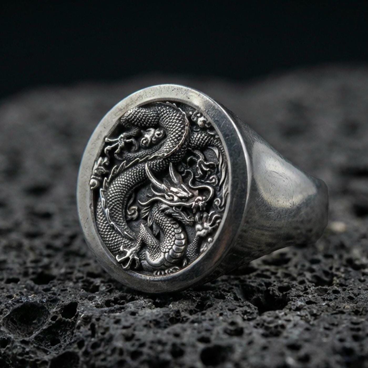 Oxidized sterling silver Chinese dragon signet ring on black volcanic stone, coiled imperial dragon relief, lunar new year jewelry