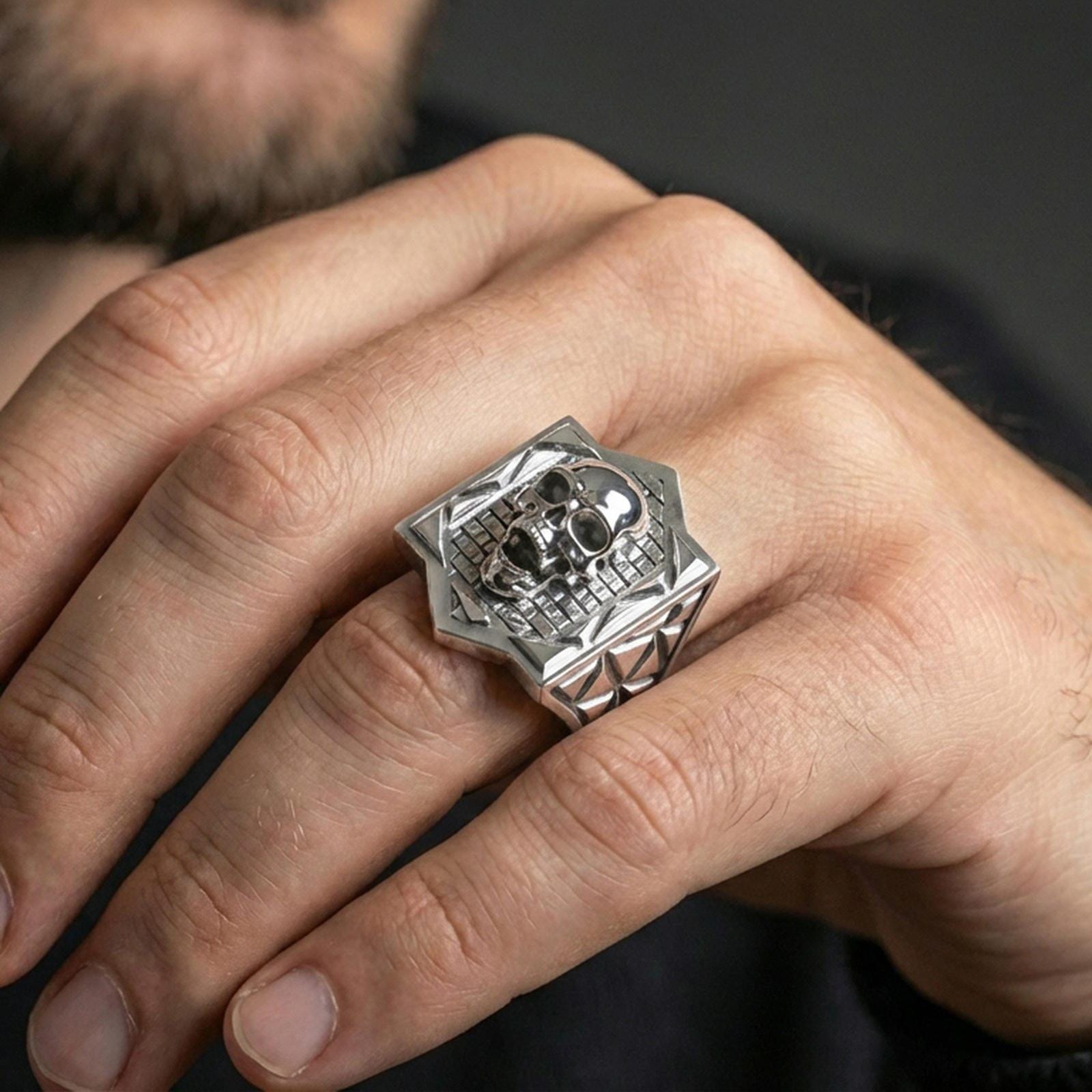 Polished sterling silver skull signet ring on a human finger, detailed skull face, statement signet ring