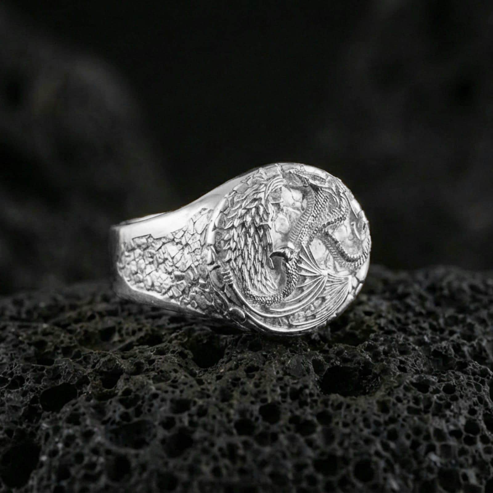 Polished sterling silver wolf and dragon ring on black volcanic stone, mythological animal design, high-detail signet style