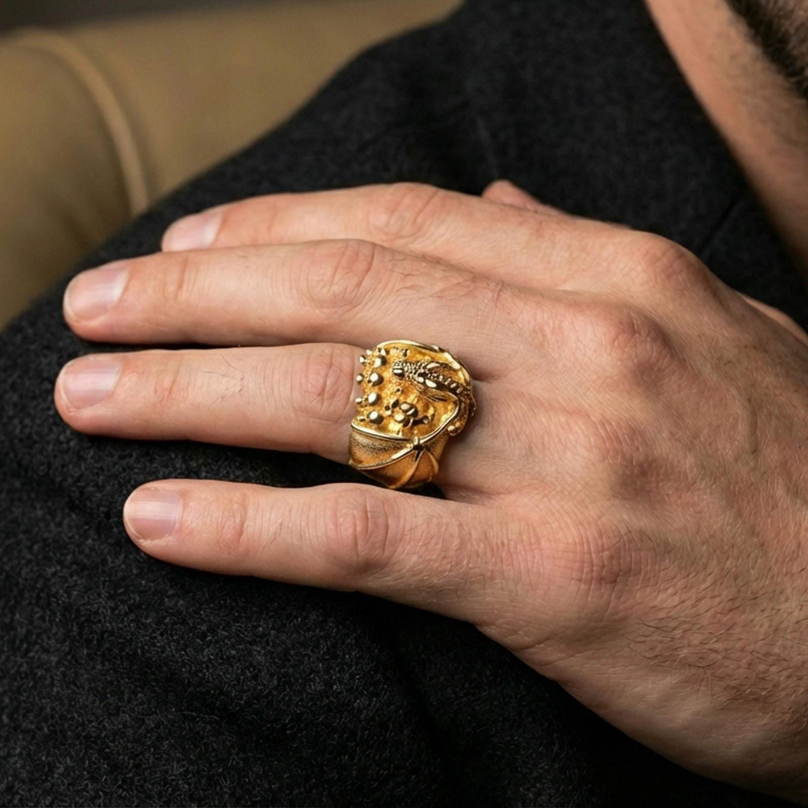 Gold plated dragon skull signet ring worn on a human finger, dark fantasy dragon jewelry, bold collectible ring