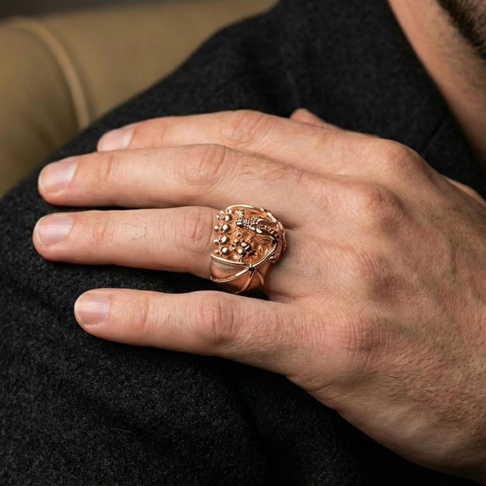 Rose gold plated dragon skull ring on a human finger, dragon and skull motif, gothic fantasy accessory