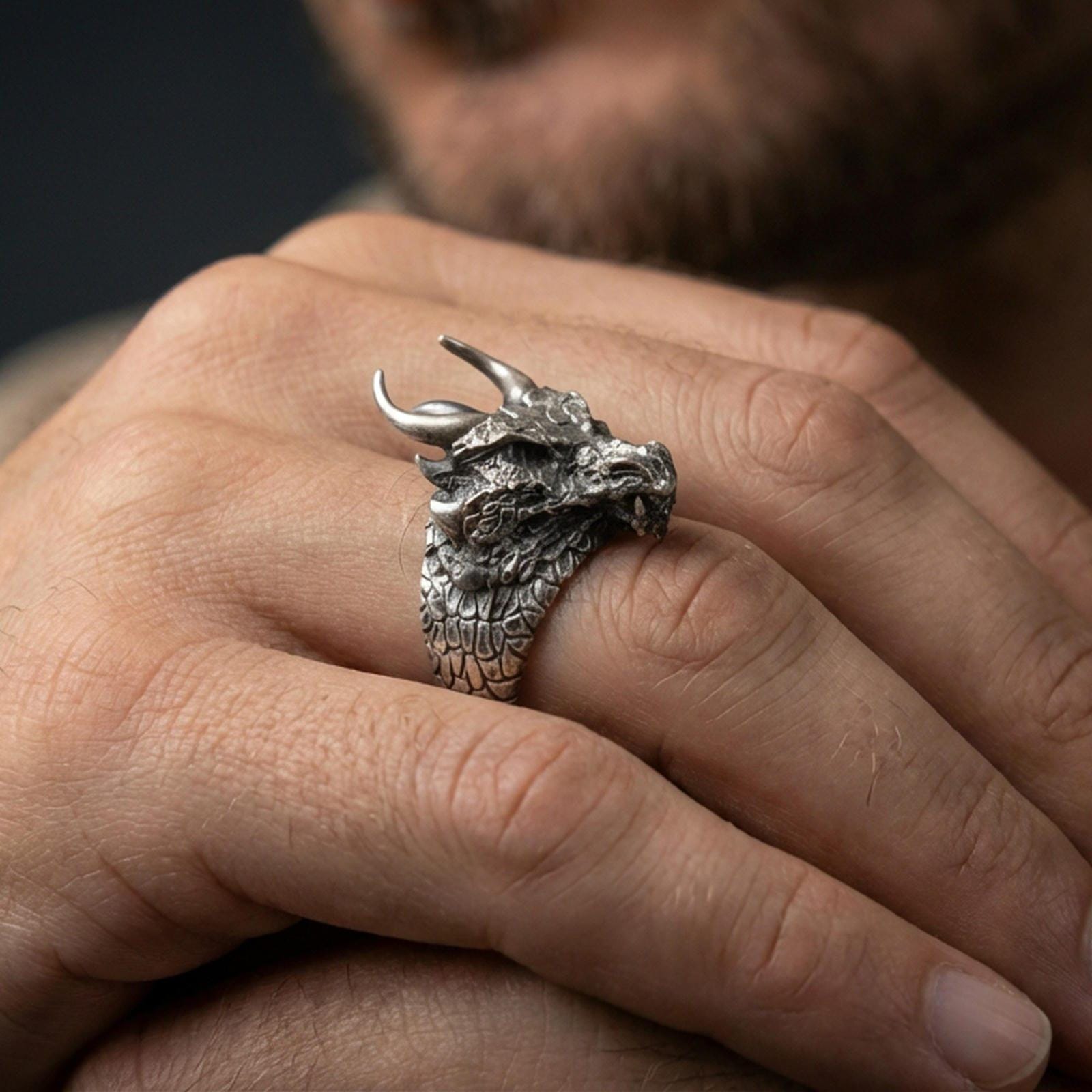 Oxidized sterling silver horned dragon ring worn on a human finger, detailed dragon head and horns, mythical statement ring