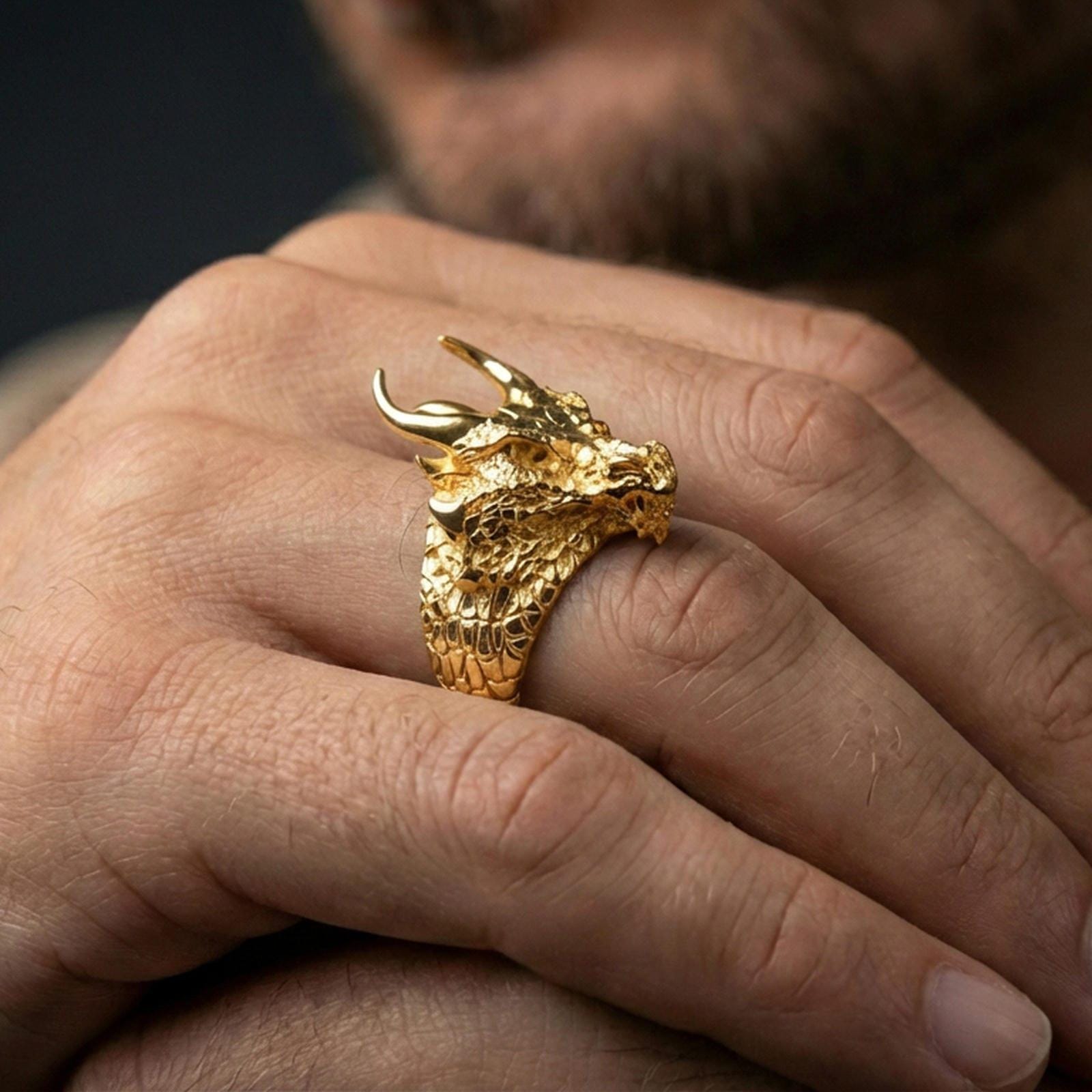 Gold plated horned dragon ring worn on a human finger, dragon head motif, bold gothic fantasy ring