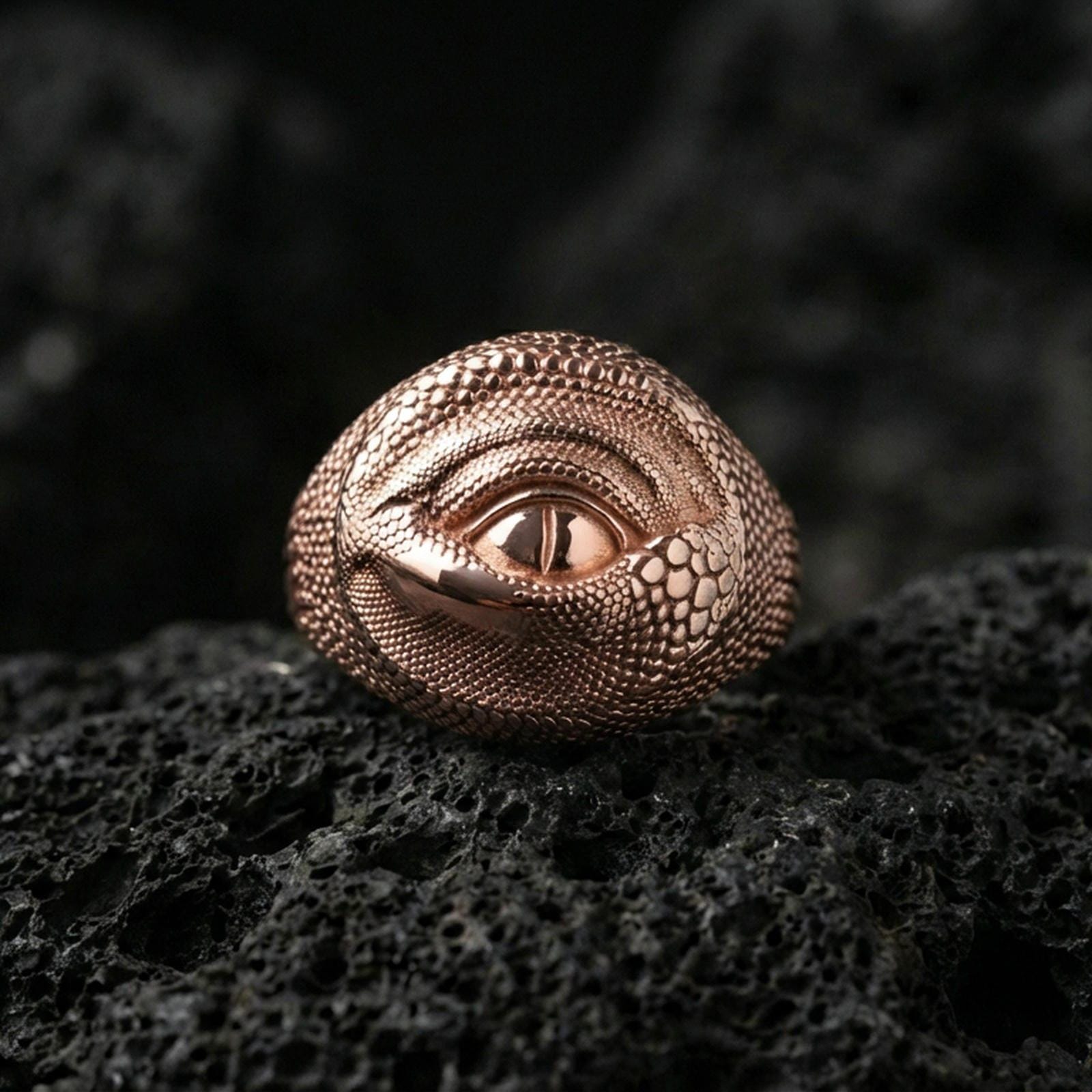 Rose gold plated dragon eye ring on black volcanic stone, scaled dragon skin texture with eye motif, gothic accessory