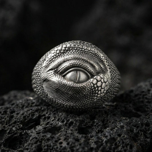 Oxidized sterling silver dragon eye ring on black volcanic stone, detailed reptile scales and slit pupil, gothic fantasy jewelry