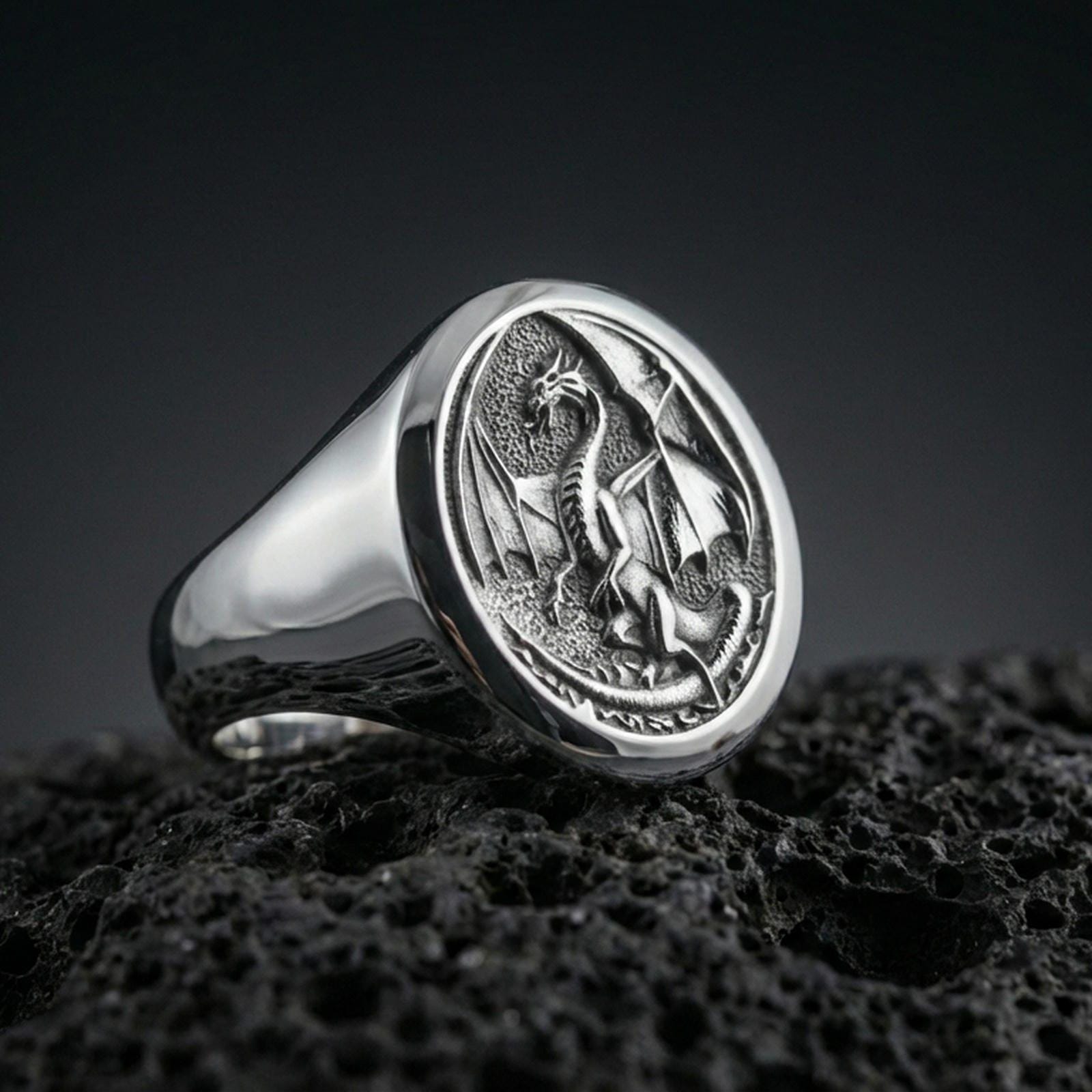 Polished sterling silver dragon signet ring on black volcanic stone, engraved medieval dragon emblem, mythical jewelry