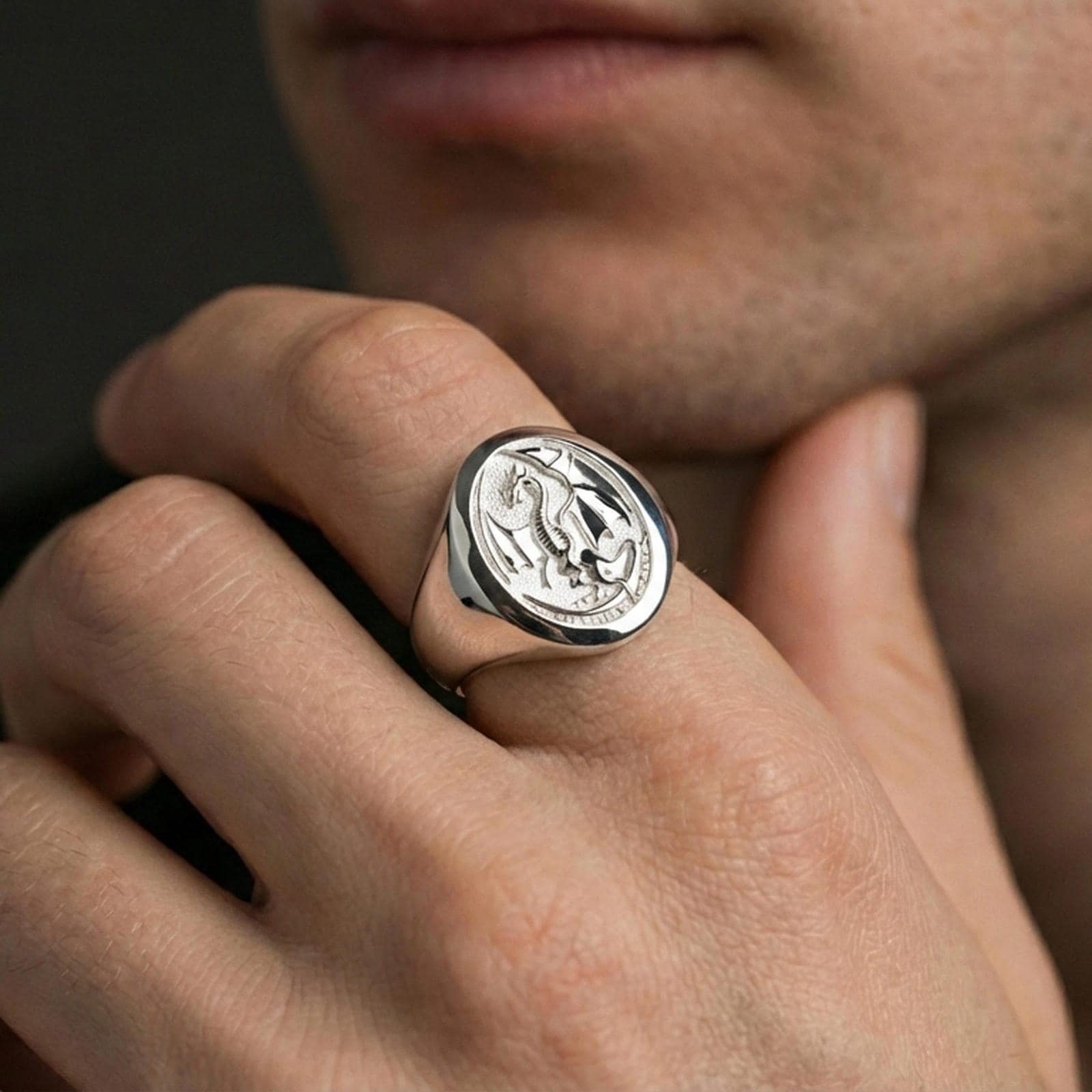 Polished sterling silver dragon signet ring on a human finger, engraved winged dragon design, statement jewelry