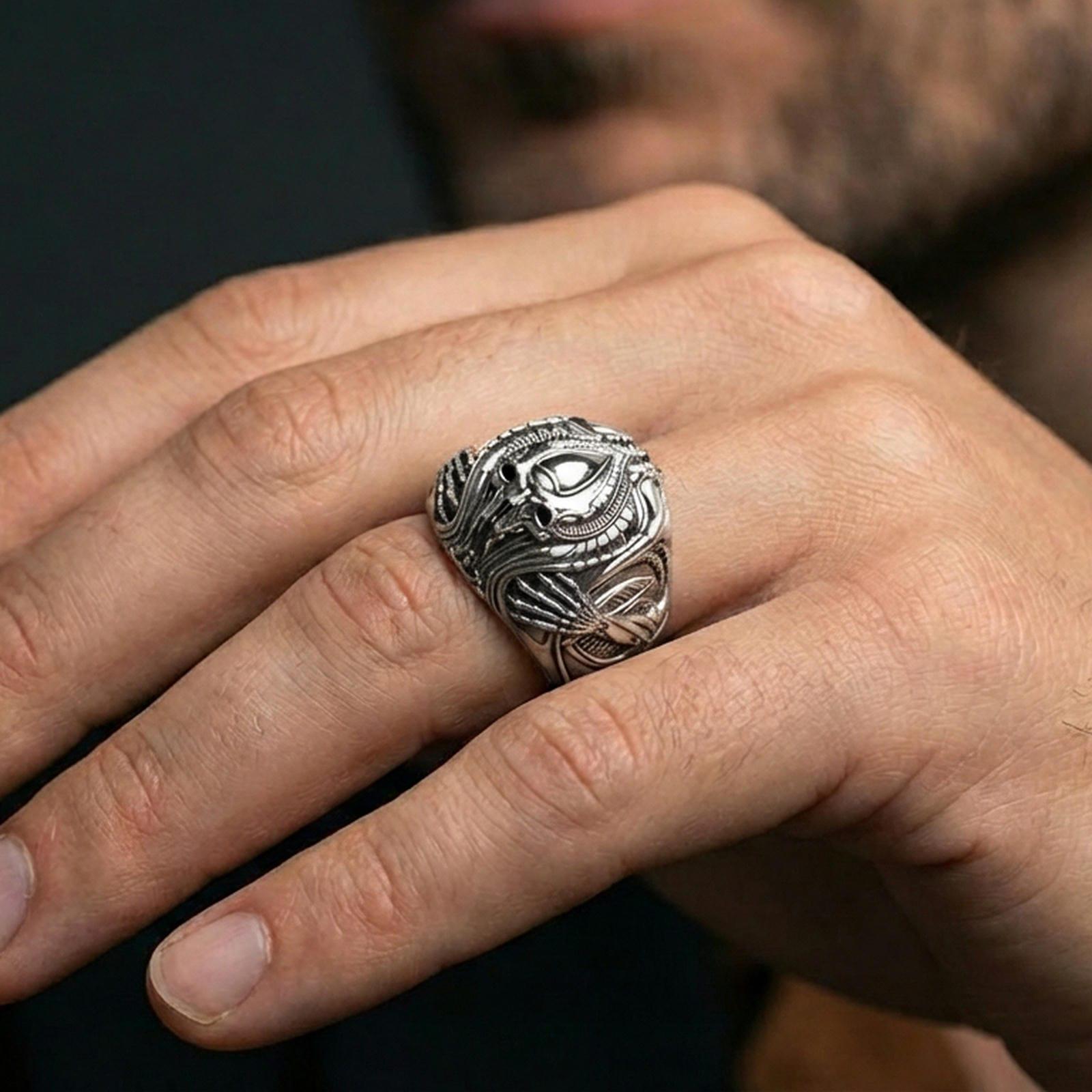 Polished sterling silver alien skull ring on a human finger, biomechanical sci-fi relief, bold gothic jewelry