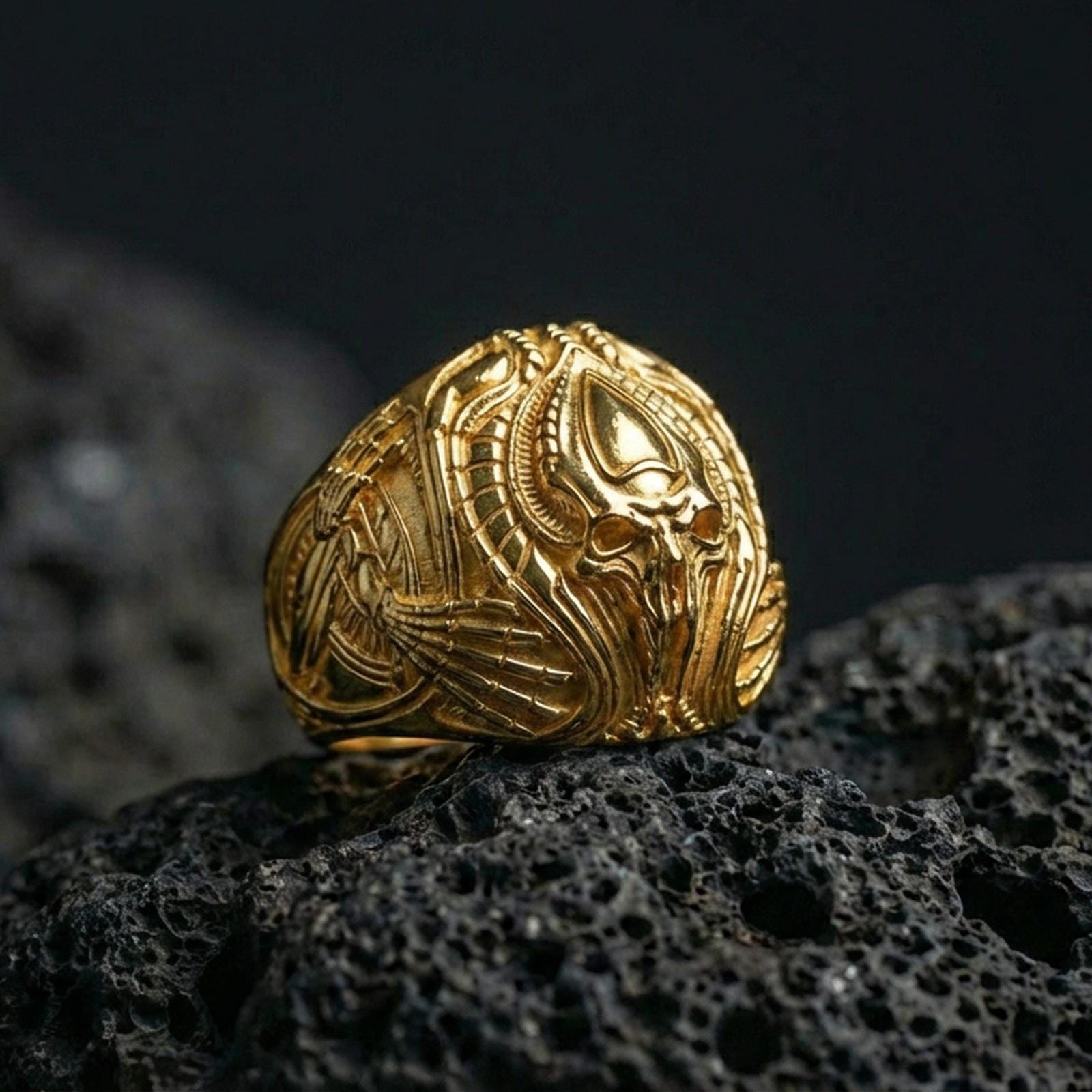 Gold plated alien skull signet ring on black volcanic stone, biomech creature skull motif, dark sci-fi jewelry