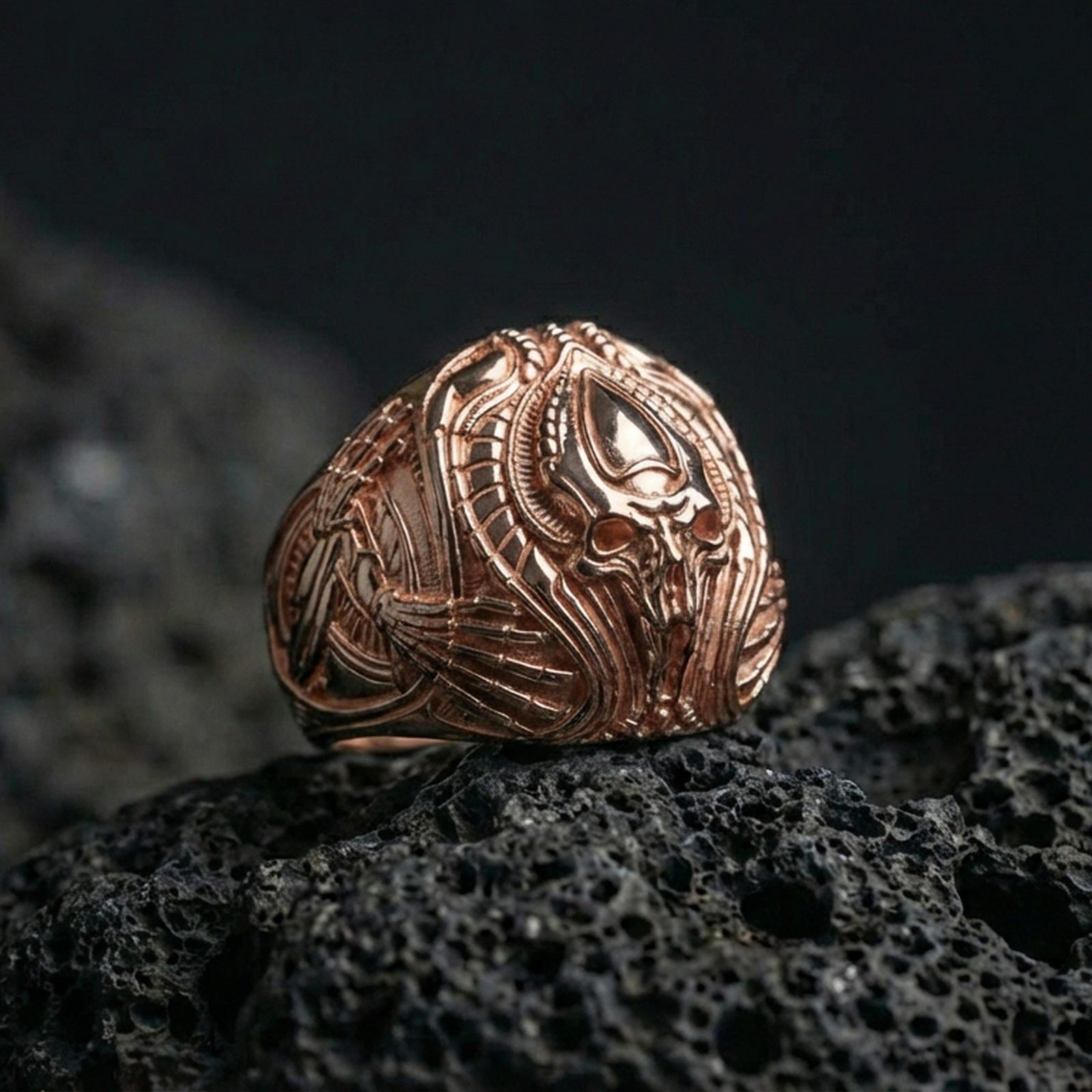 Rose gold plated alien skull ring on black volcanic stone, biomechanical gothic skull detailing, futuristic signet