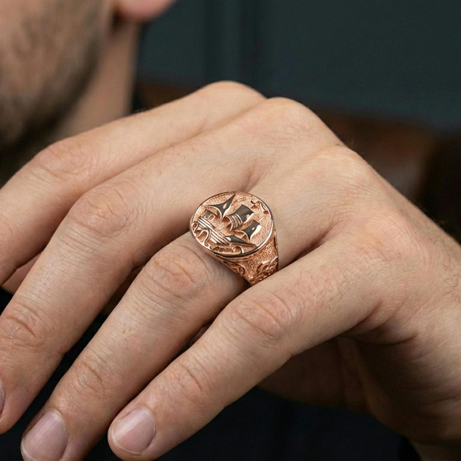 Rose gold plated Flying Dutchman ship signet ring on a human finger, classic sailing ship motif, nautical men’s ring