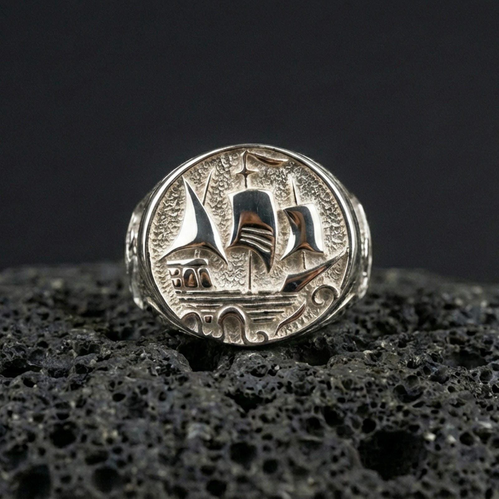 Polished sterling silver Flying Dutchman ship signet ring on black volcanic stone, engraved sailing vessel design, nautical jewelry