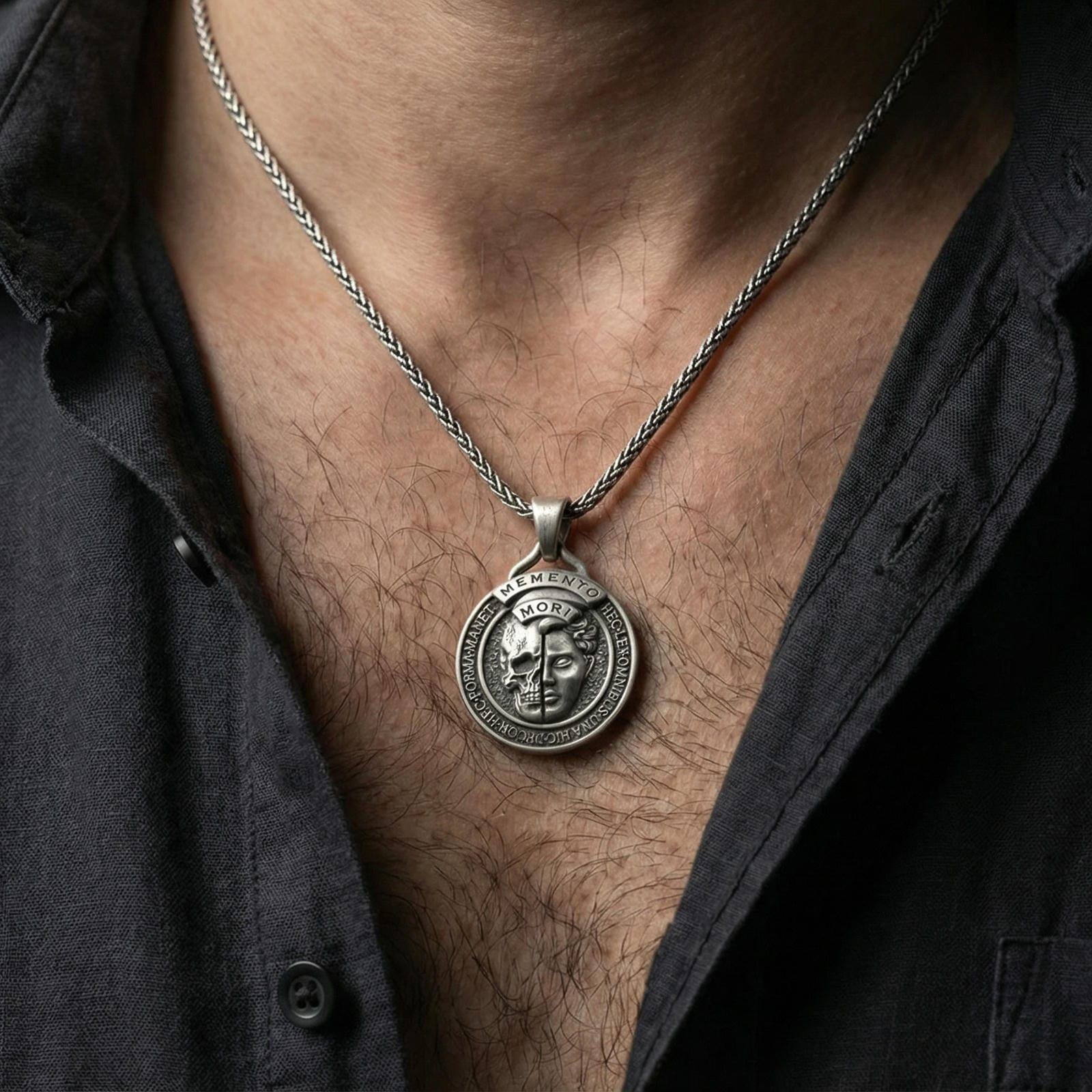 Oxidized memento mori pendant worn on neck on a braided chain, centered chest framing, moody lifestyle studio shot