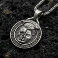 Load image into Gallery viewer, Oxidized sterling silver memento mori coin pendant on textured volcanic rock, split skull and face relief, macro studio shot
