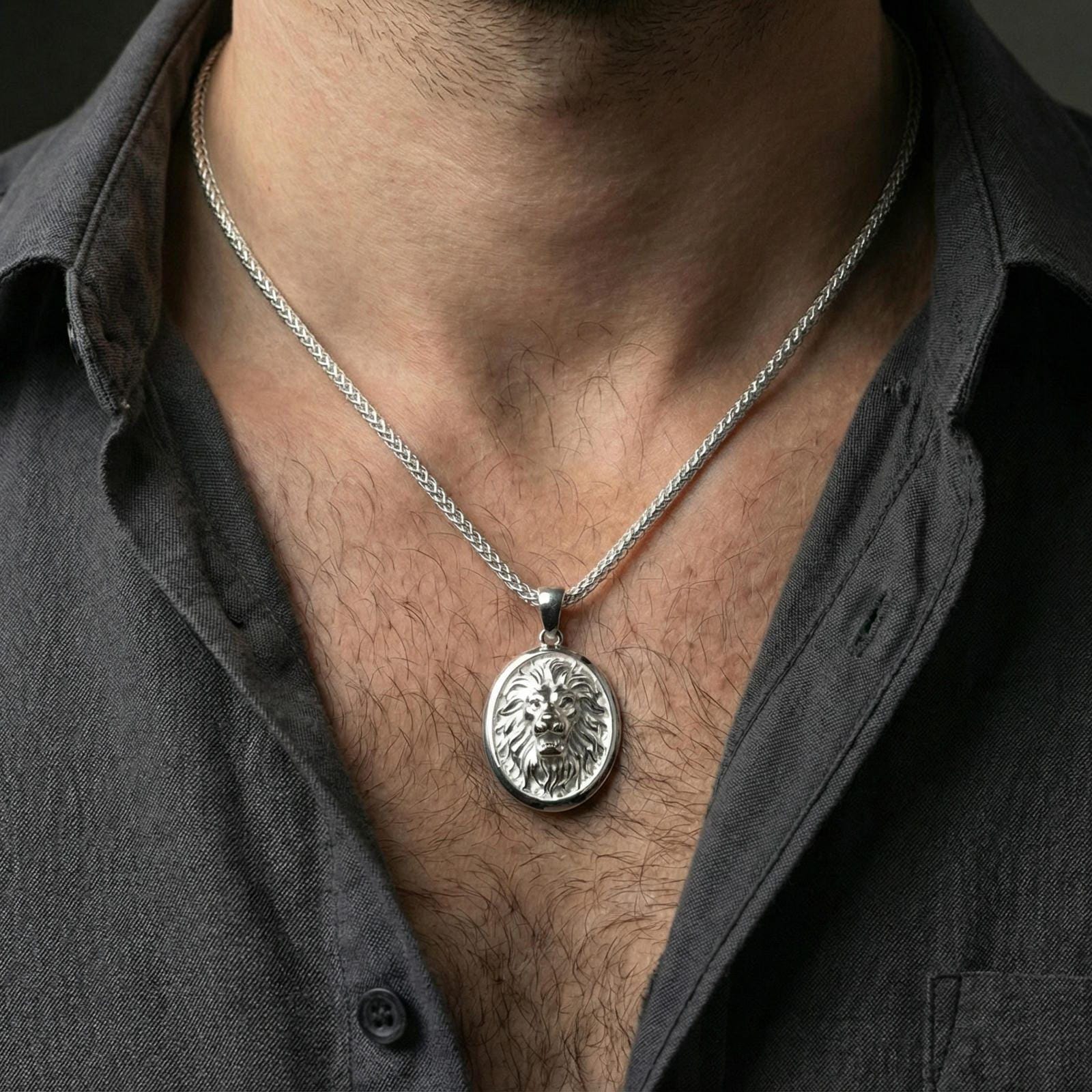 Polished silver lion head oval pendant necklace worn on neck, close lifestyle crop, clear mane texture and raised lion relief