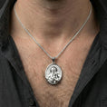 Load image into Gallery viewer, Polished silver St Francis oval pendant necklace worn on neck, close lifestyle crop, clear halo relief and portrait details
