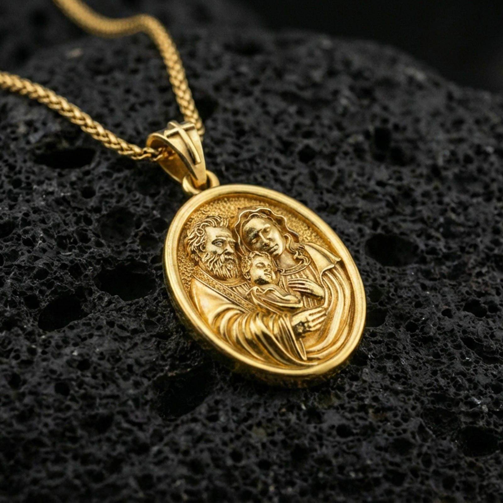 Gold plated Holy Family pendant on porous volcanic rock backdrop, devotional oval medal with detailed family relief, high-contrast lighting