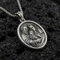 Load image into Gallery viewer, Oxidized sterling silver Holy Family oval medal on textured volcanic rock, detailed Mary Joseph and Child relief, macro studio shot
