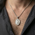 Load image into Gallery viewer, Polished silver Jesus Christ oval medallion necklace worn on neck, close lifestyle crop, clear relief details and antique oval frame

