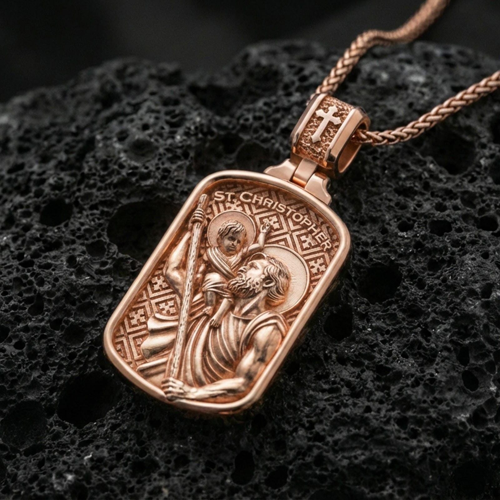 Rose gold plated St Christopher medal pendant on matte volcanic stone, intricate religious relief and patterned background, sharp macro focus