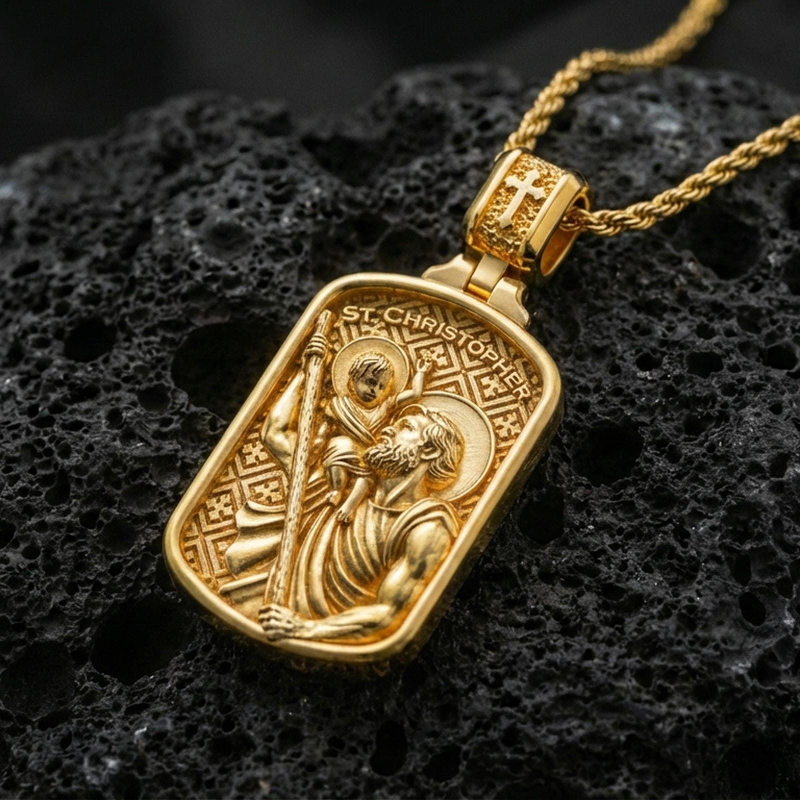 Gold plated Saint Christopher pendant on porous volcanic rock backdrop, rectangular devotional medal with child and staff relief, high-contrast lighting