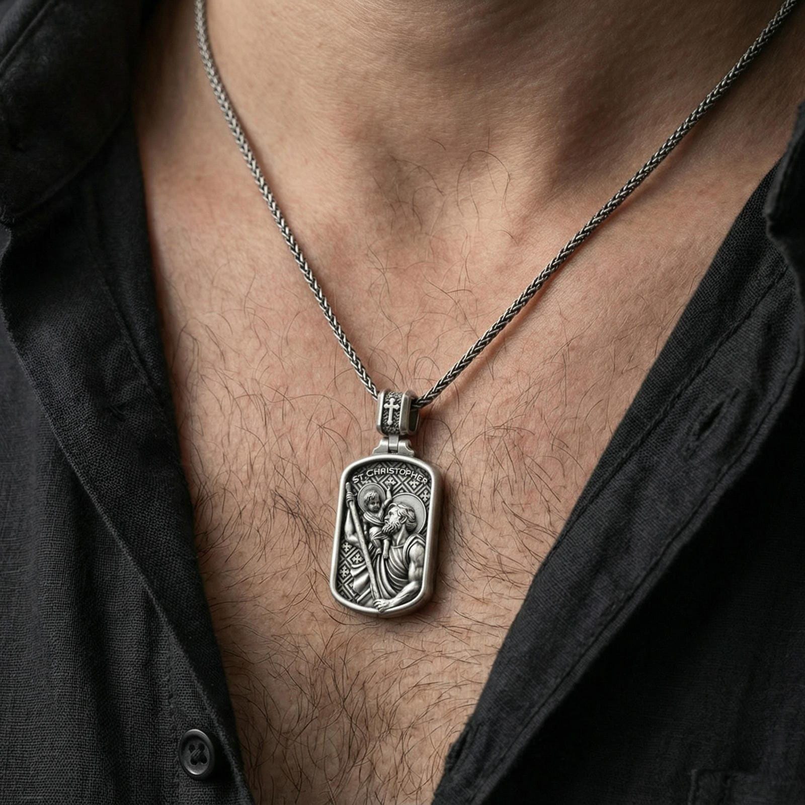 Oxidized sterling silver Saint Christopher pendant worn on neck on a braided chain, centered chest framing, moody lifestyle studio shot