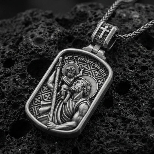 Oxidized sterling silver Saint Christopher pendant on textured volcanic rock, rectangular medal with saint carrying child relief, macro studio shot