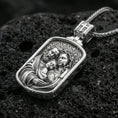 Load image into Gallery viewer, Polished silver Holy Family necklace pendant on dark volcanic stone, crisp engraved faces and geometric patterned background, premium close-up
