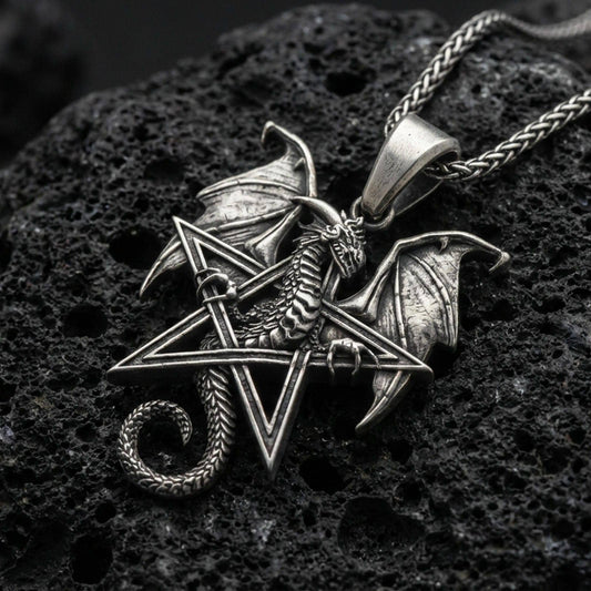 Oxidized sterling silver pentagram dragon pendant on textured volcanic rock, winged dragon wrapped around star frame, macro studio shot