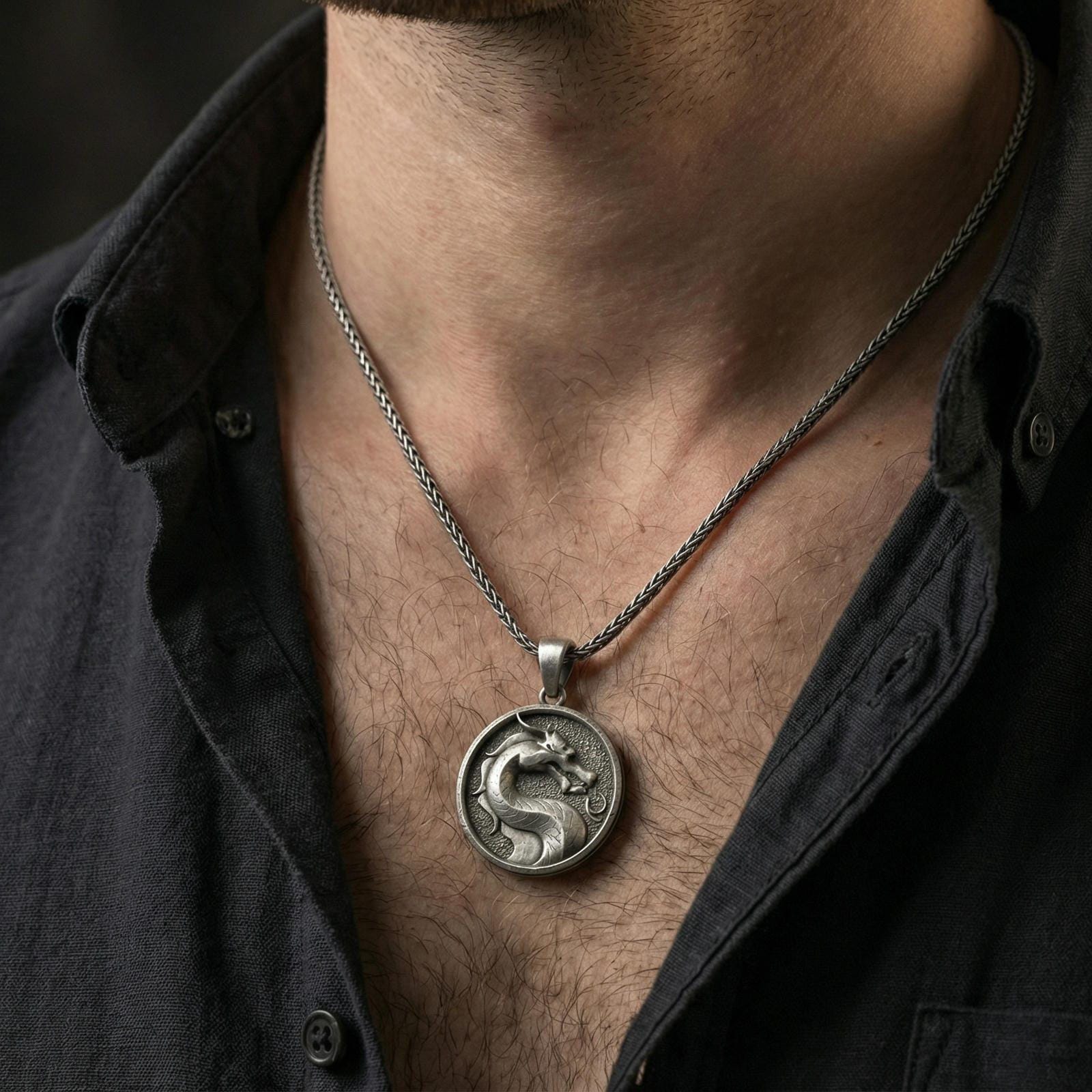 Oxidized sterling silver Mortal Kombat dragon pendant worn on neck on braided chain, round gaming symbol medallion, dark lifestyle shot