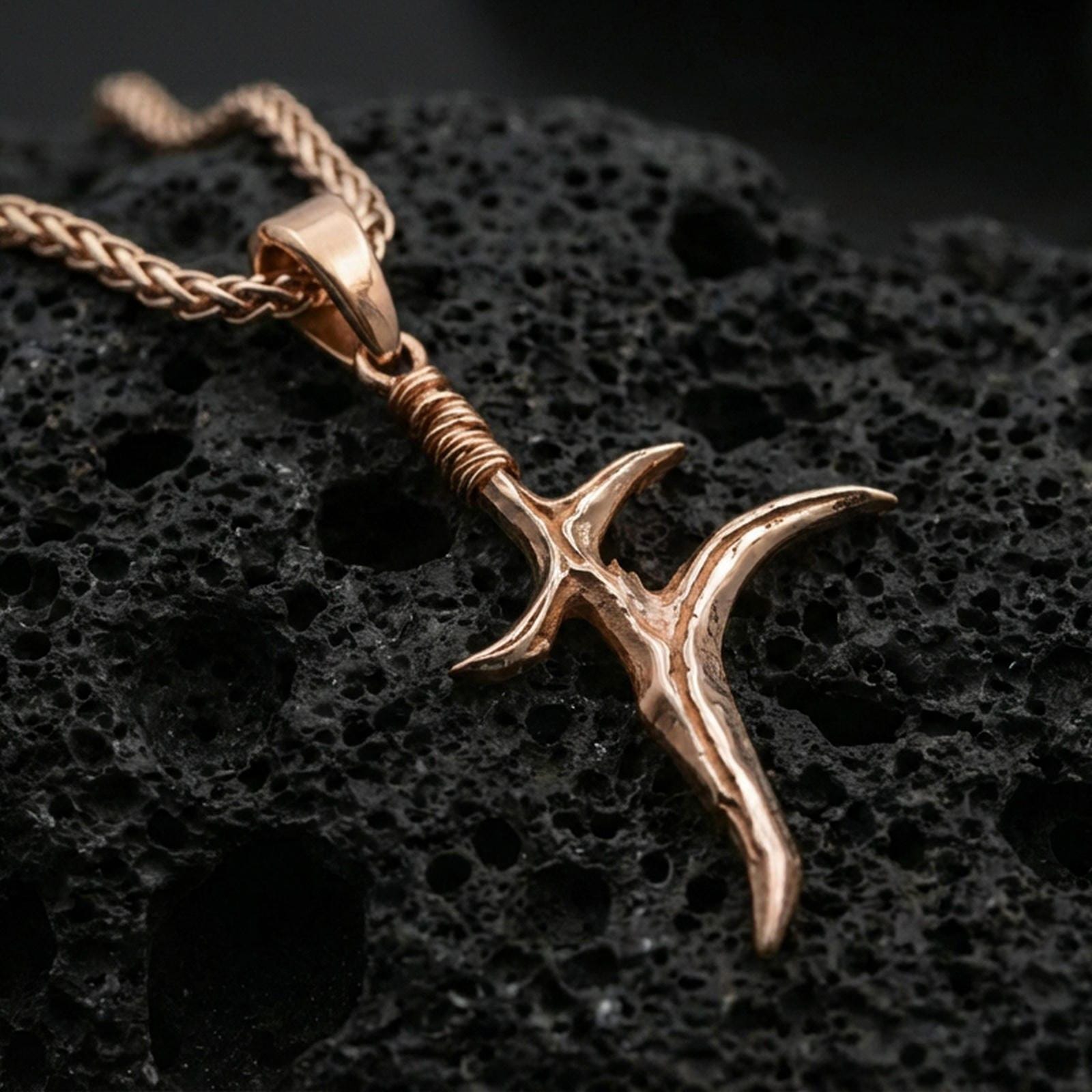 Rose gold plated black knife dagger pendant on volcanic stone surface, fantasy videogame inspired charm necklace, sharp detail