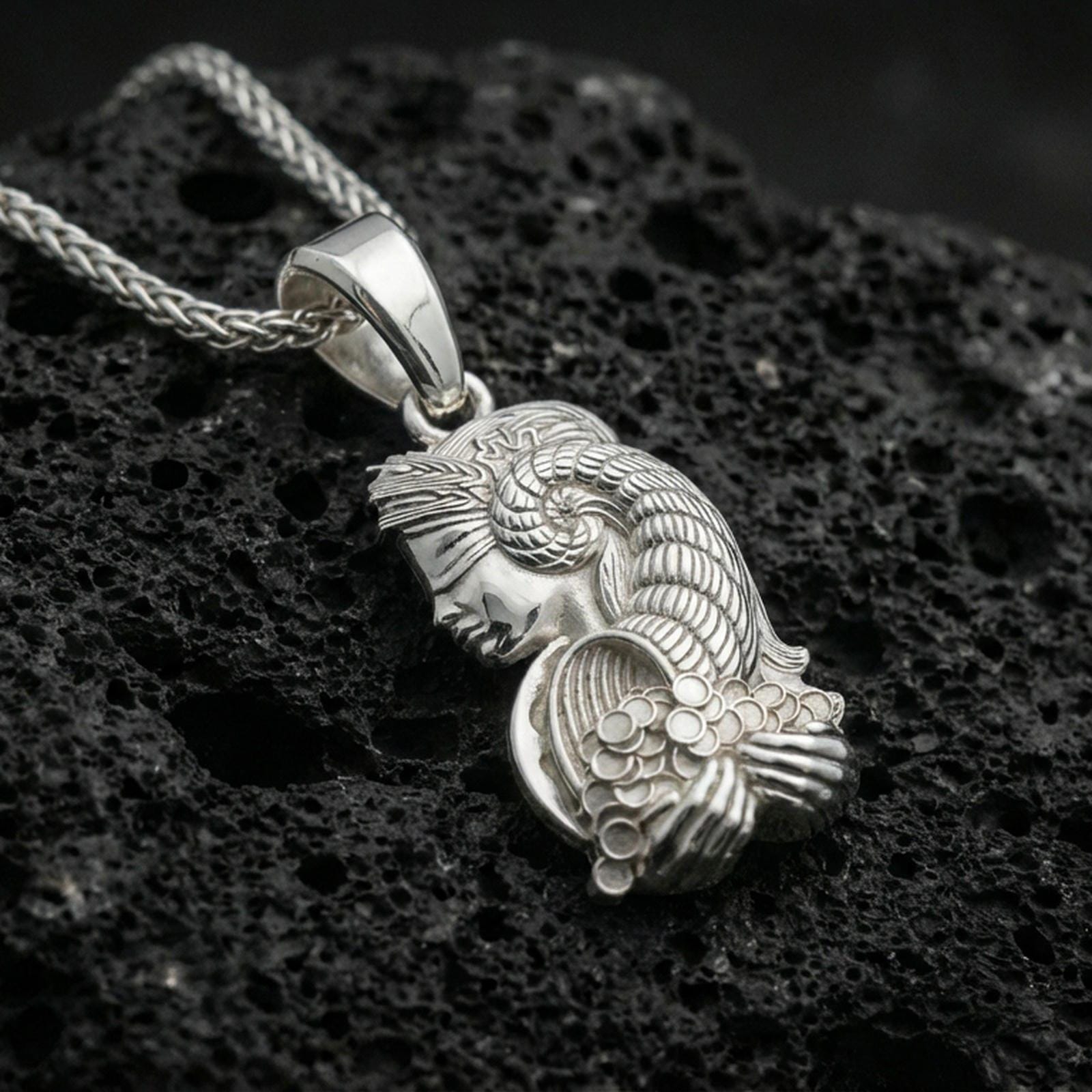 Polished silver Fortuna pendant necklace on porous volcanic stone, Roman goddess profile with cornucopia, macro close-up