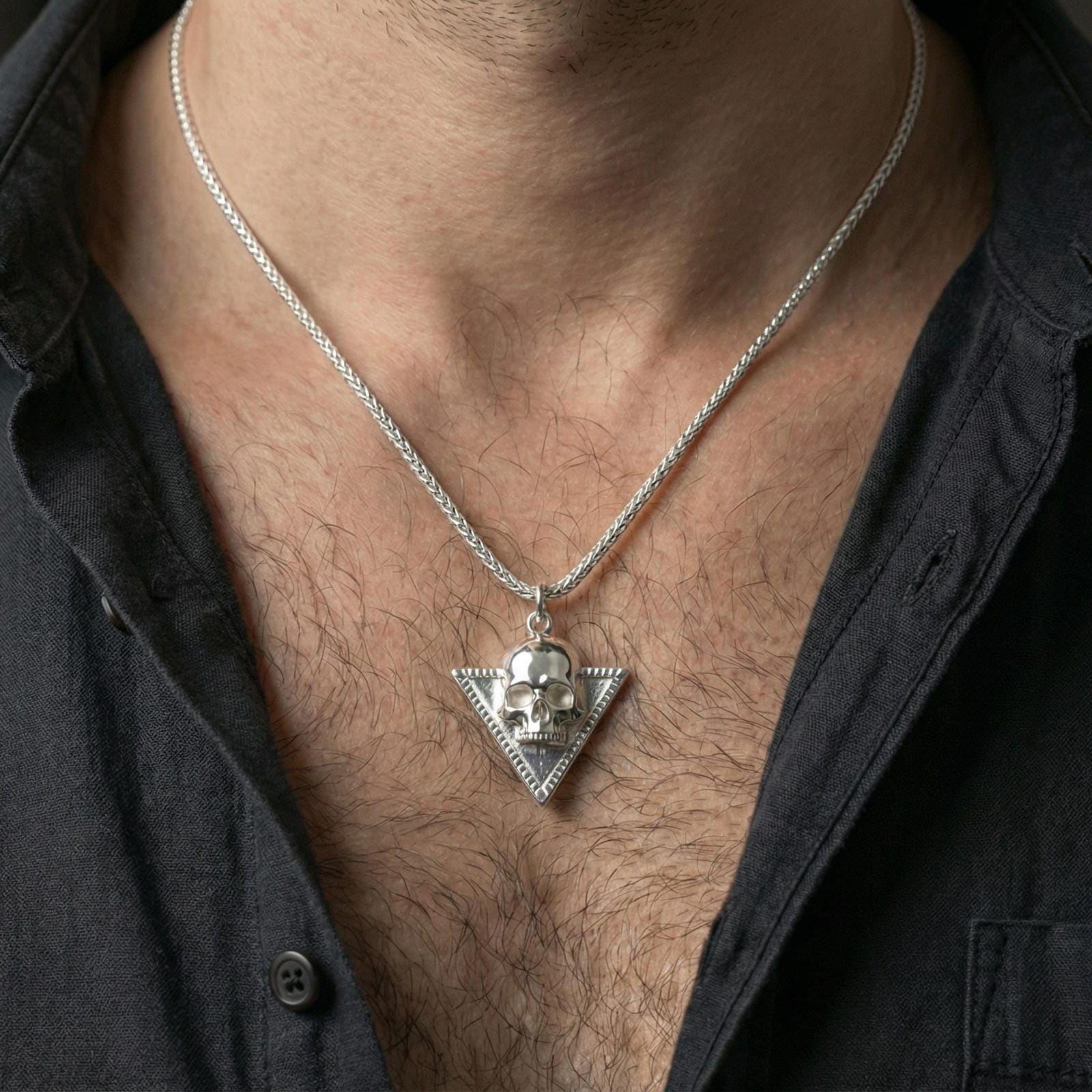 Polished silver Absolute’s talisman skull necklace worn on neck, BG3 fan pendant on braided chain, clean close-up
